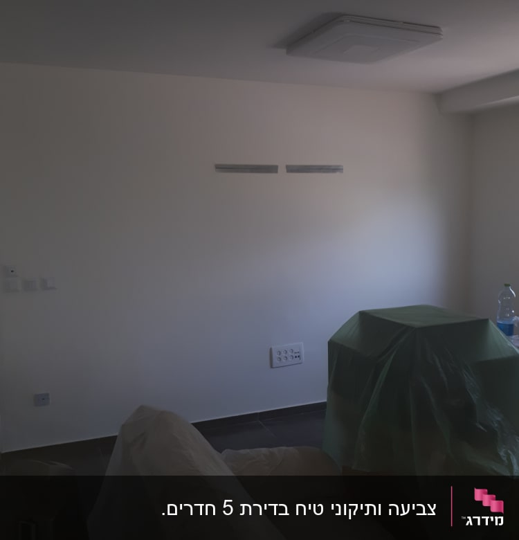 קיר צבוע עם רהיטים מכוסים בניילון